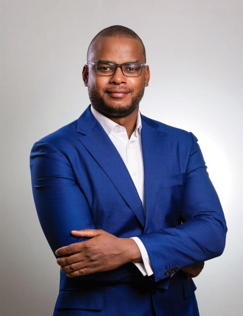 A corporate photograph of a businessman in a dark…